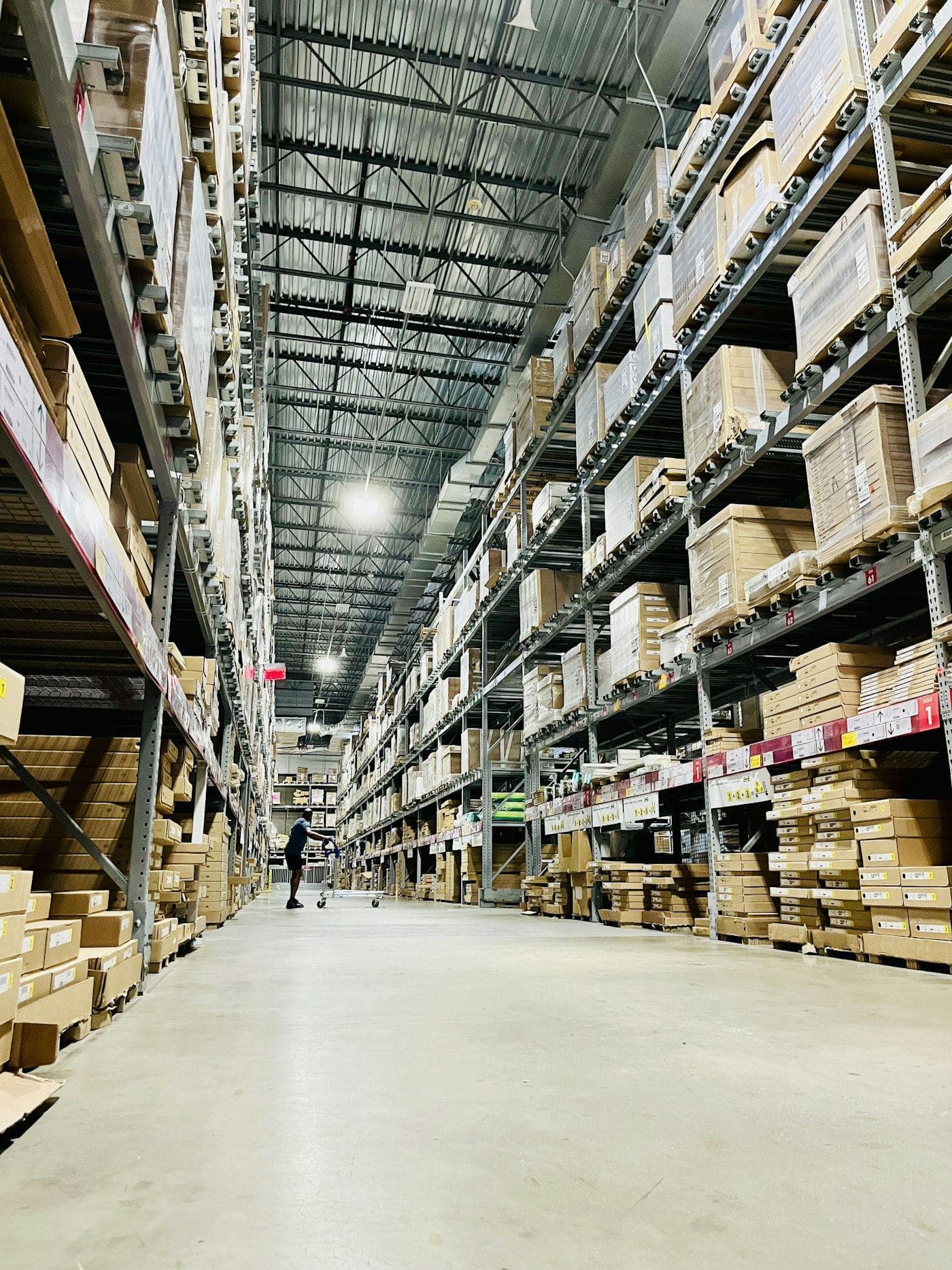 Long warehouse aisle lined with shelves of cartons